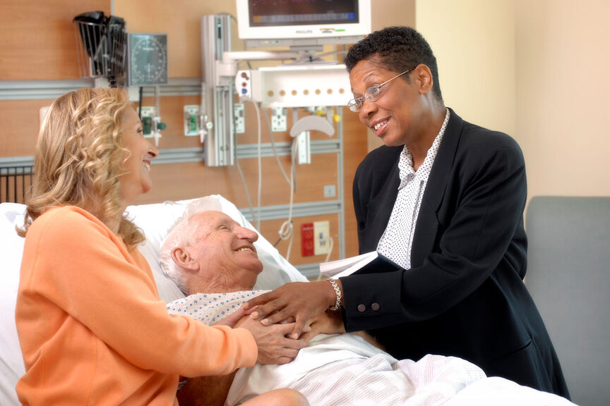 A hospital chaplain meets with a patient and family member