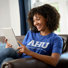 A female AHU students uses and ipad at her home