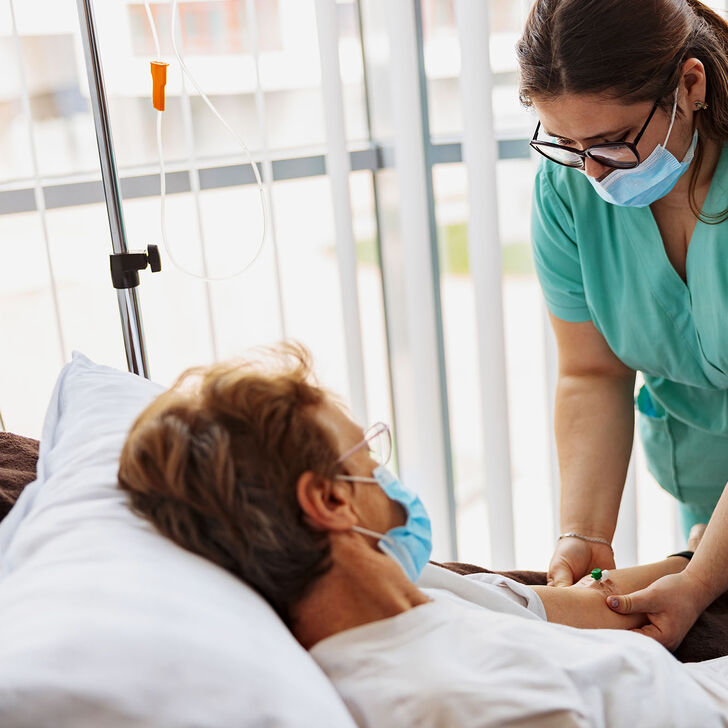 A registered nurse places an IV drip on a patient