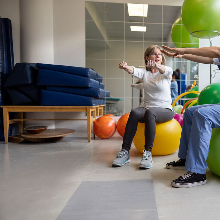 A female occupational therapist works with a patient using swiss exercise balls