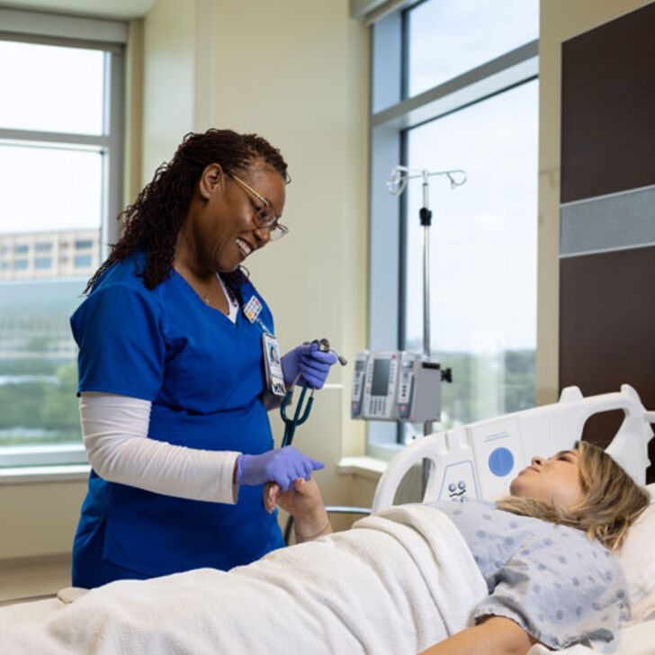 nurse smiles at patient in hospital room