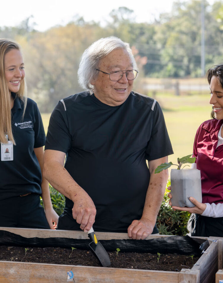 two occupational therapy students helping geriatric patient with gardening