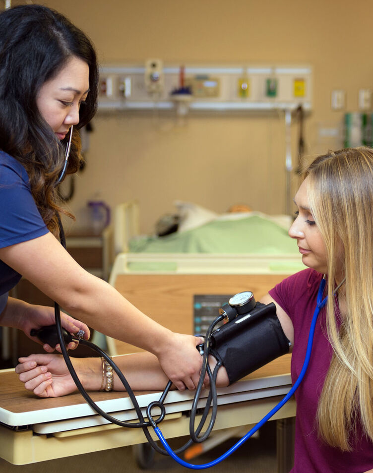 A female nursing student taking a blood pressure reading of another student
