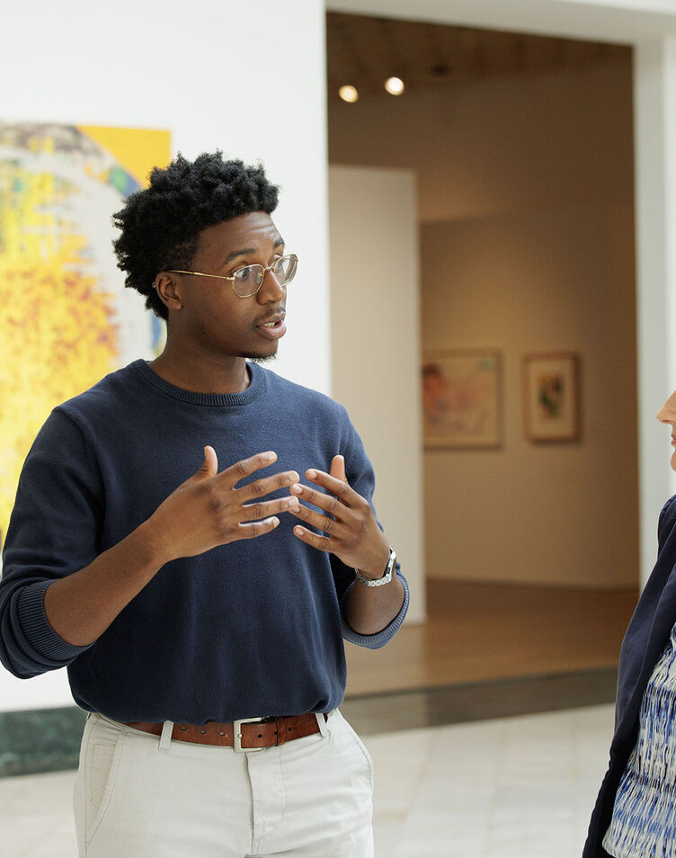 A student converses with a teacher in an art museum